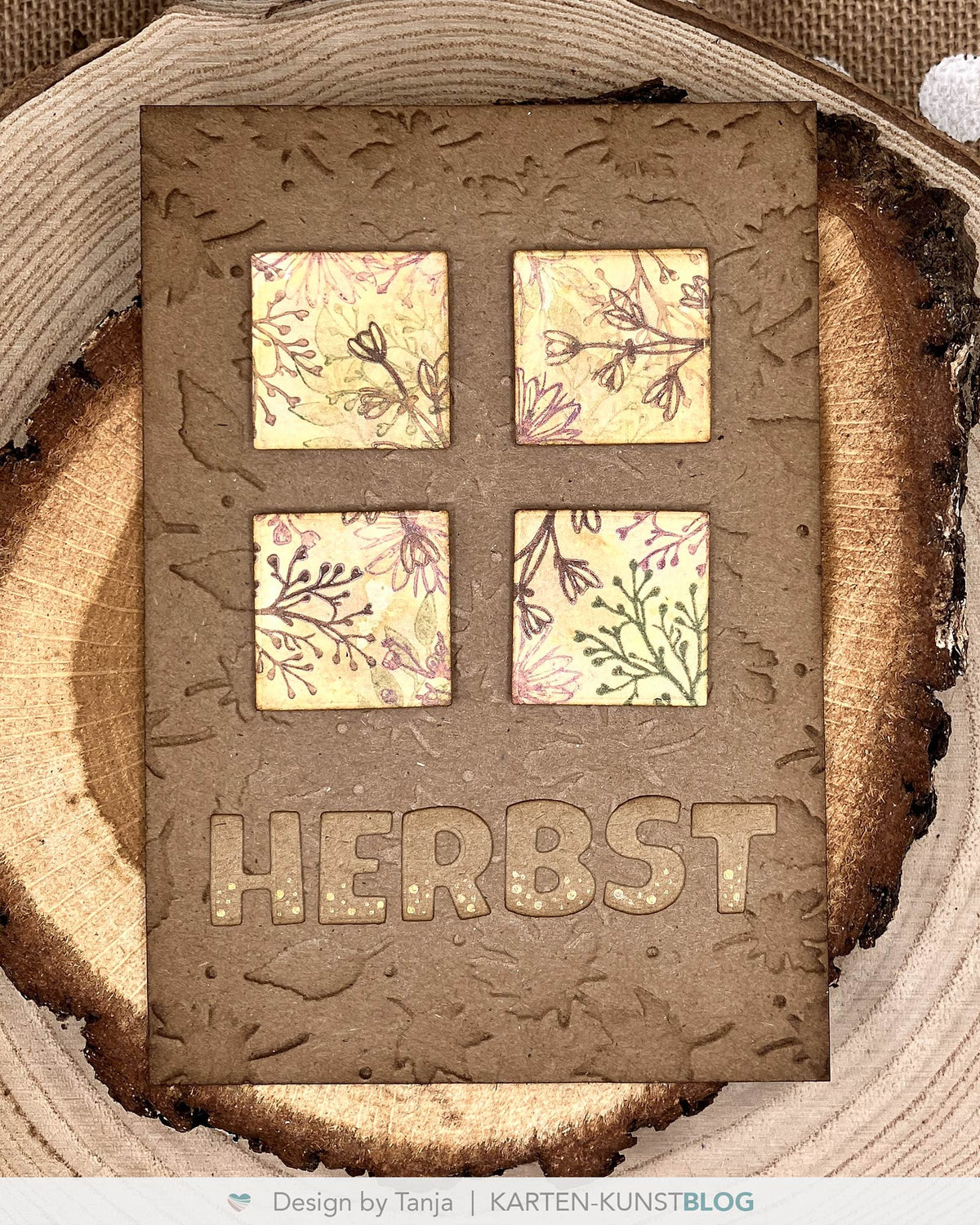 Eine herbstliche Karte aus strukturiertem Kraftpapier mit vier quadratischen Feldern, die mit feinen Blättern und Zweigen bestempelt sind. Darunter steht groß das ausgestanzte Wort „HERBST“.