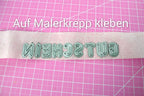 Buchstaben-Schablonen auf Malerkreppband kleben, und dann das ganze Wort zum Stanzen auf das Papier kleben