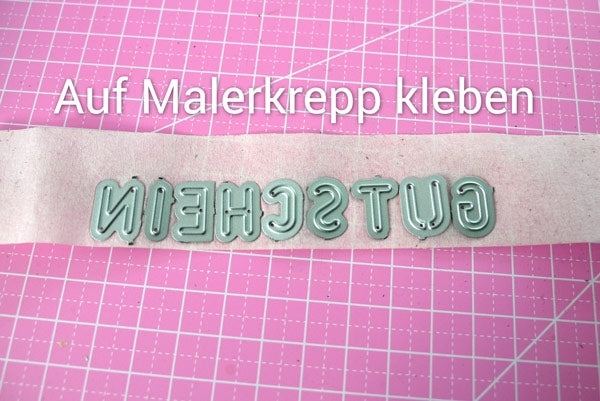 Buchstaben-Schablonen auf Malerkreppband kleben, und dann das ganze Wort zum Stanzen auf das Papier kleben
